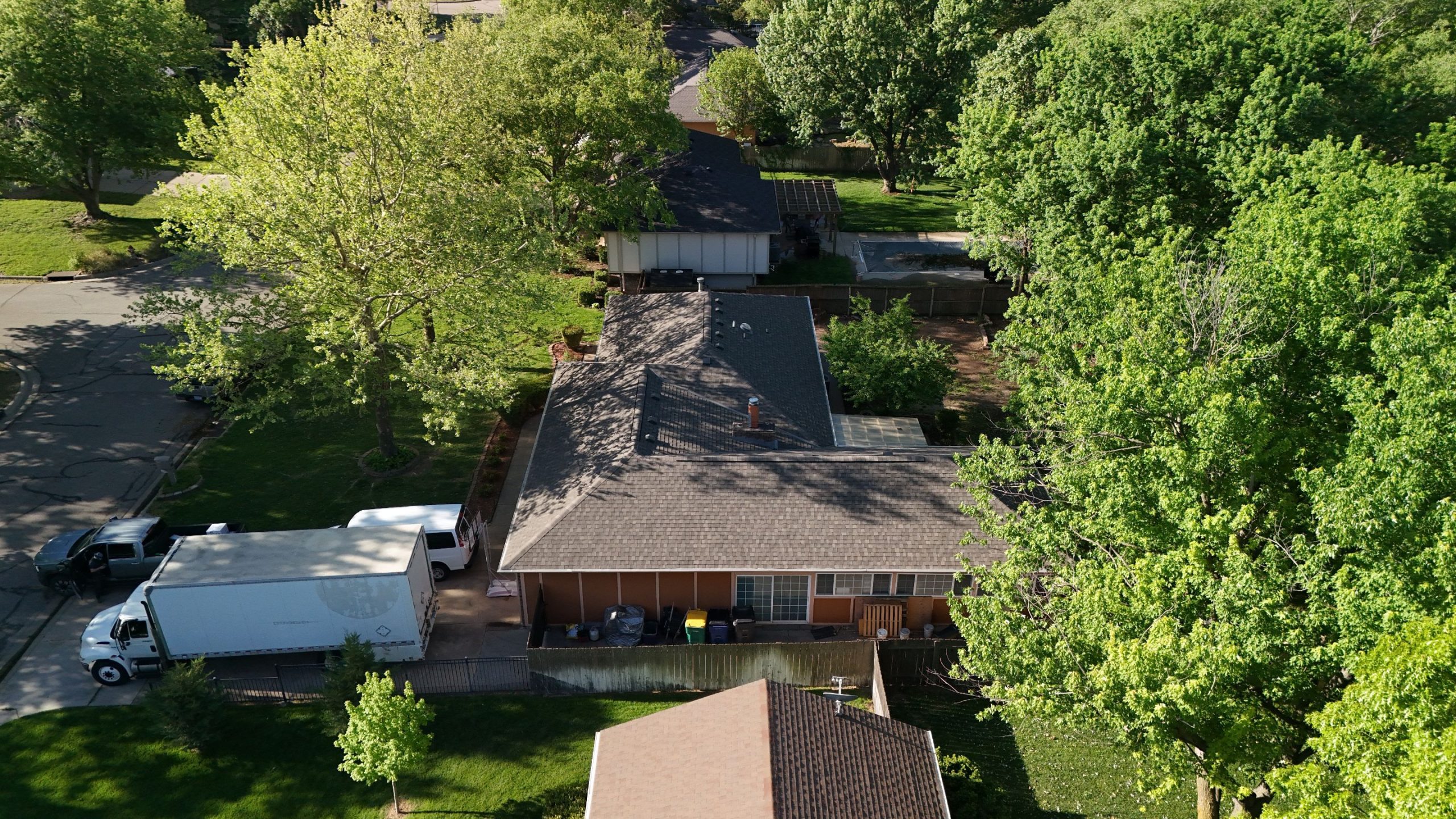 default Solid Rock Commercial Roofing Aerial view of a suburban neighborhood with tree-lined streets, single-story houses, and visible backyards.